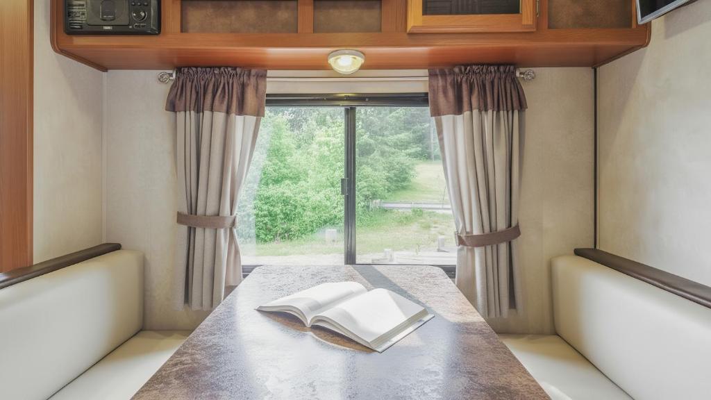 ein Buch, das auf einem Tisch vor einem Fenster liegt in der Unterkunft Goseong Jjun Camping Pension in Goseong