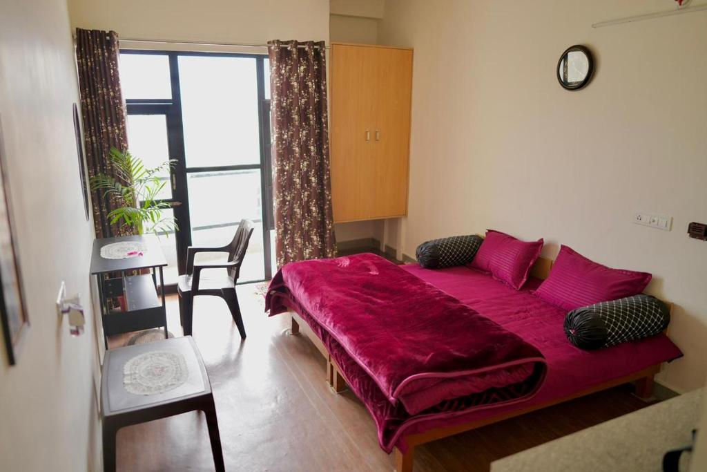 een woonkamer met een paarse bank voor een raam bij LVMR MIDTOWN STUDIO APARTMENT Shamshi in Kulu