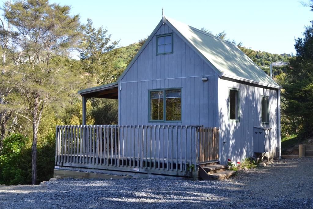 a small blue house with a white fence at Te Mata Lodge in Tapu