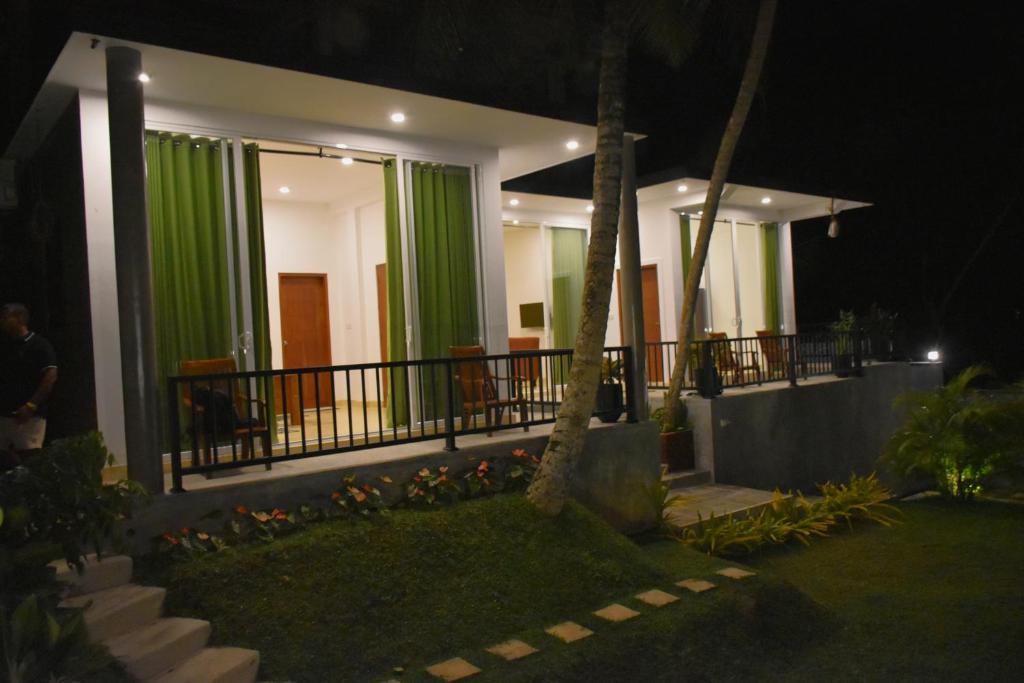 a house with green curtains on the balcony at night at Oasi house in Unawatuna