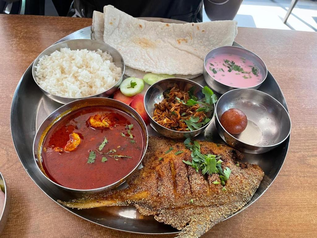 a plate of food with meat and bowls of food at Golden Wave Cottage in Revadanda