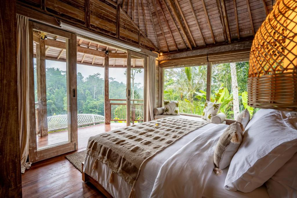 een slaapkamer met een bed in een kamer met ramen bij Moonlit Jungle in Seribatu