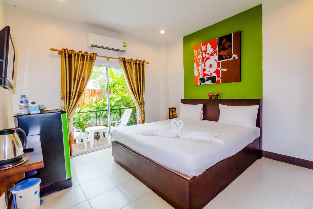 a bedroom with a bed with a green wall at Baan Yuyen Karon Guesthouse in Karon Beach