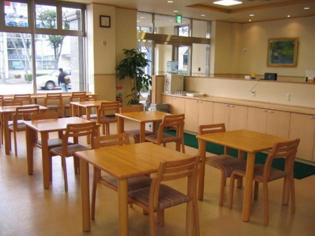 土浦市にあるCrown Hills Tsuchiuraekihigashiの木製テーブルと椅子が備わるレストラン