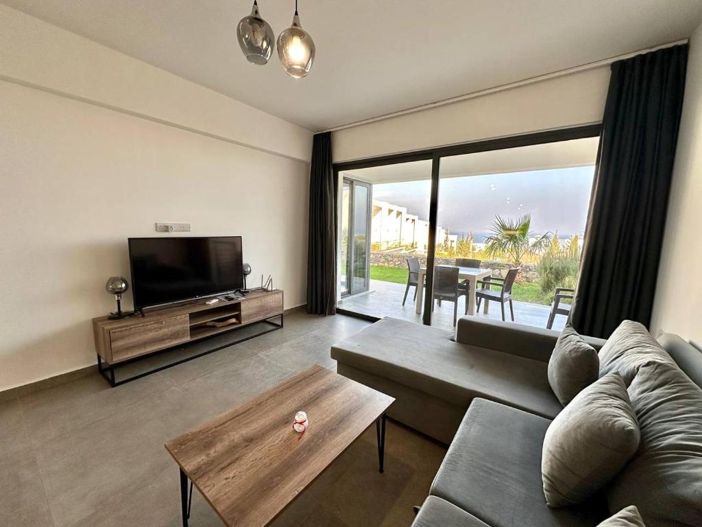 een woonkamer met een bank, een tv en een tafel bij Retreat, block A2, unit 1 in Ayios Nikolaos