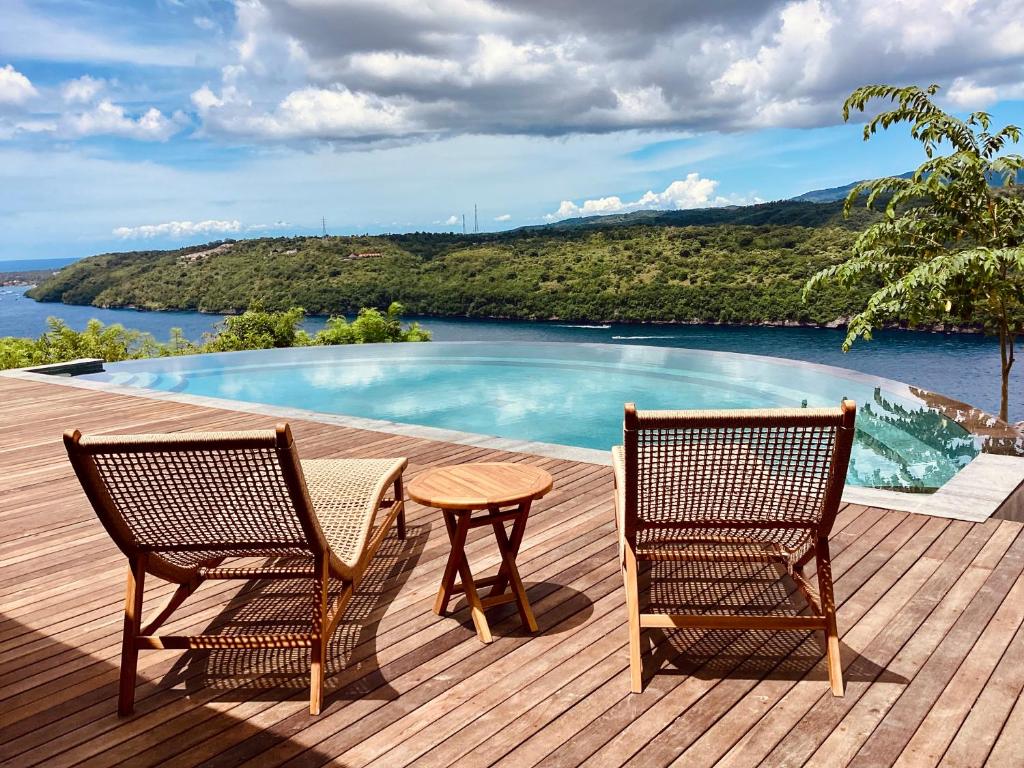 twee stoelen en een tafel op een terras met een zwembad bij Les Terrasses Ceningan in Nusa Lembongan