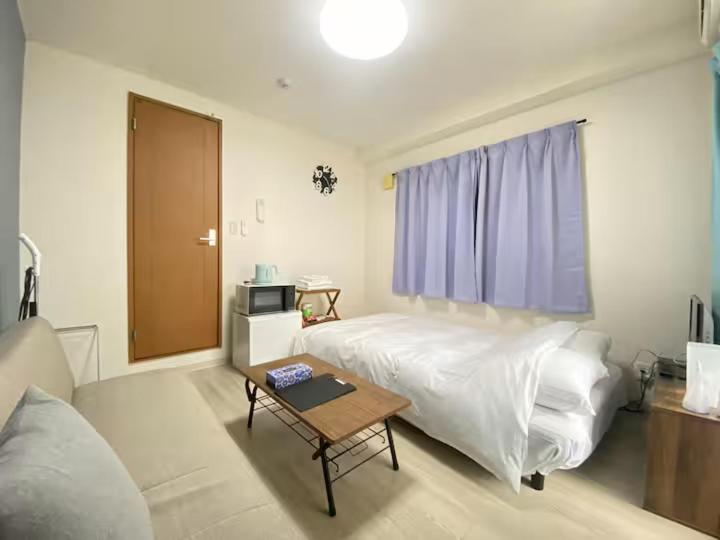 una camera da letto con un letto e un tavolo in una stanza di マルチステイ大阪京橋 ad Osaka