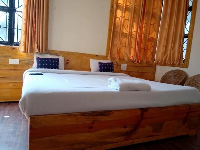 ein Schlafzimmer mit einem großen weißen Bett mit blauen Kissen in der Unterkunft Shillong City Hotel in Shillong