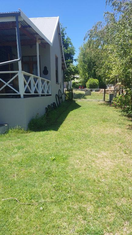 a white house with a grass yard in front of it at Tevreden in Rhodes