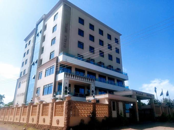 a tall white building with a fence in front of it at Saala Hotel Limited in Gatunga