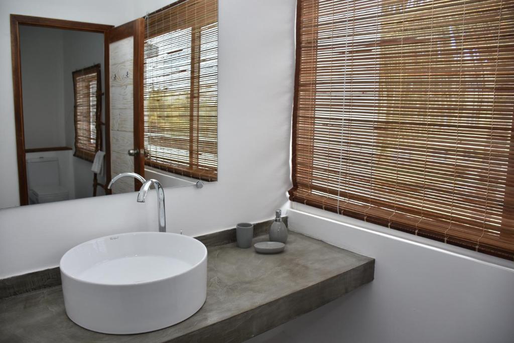 La salle de bains est pourvue d'un grand lavabo blanc et d'une fenêtre. dans l'établissement Stella Rina, à Grand Baie