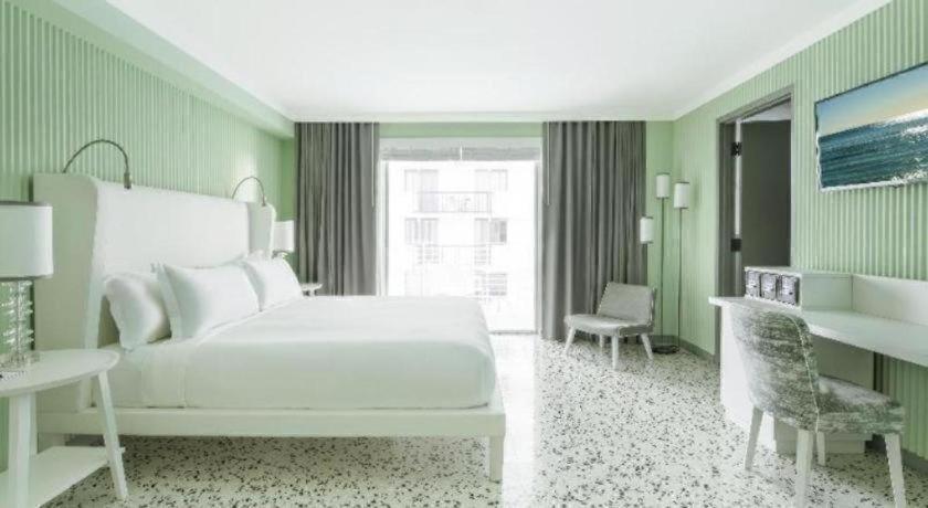 ein Schlafzimmer mit einem weißen Bett und einem Schreibtisch in der Unterkunft COMO Metropolitan Miami Beach in Miami Beach