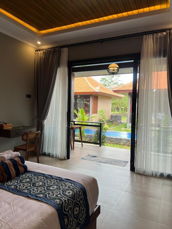 een slaapkamer met een bed en een grote glazen schuifdeur bij Adiuma Cottage Ubud in Ubud