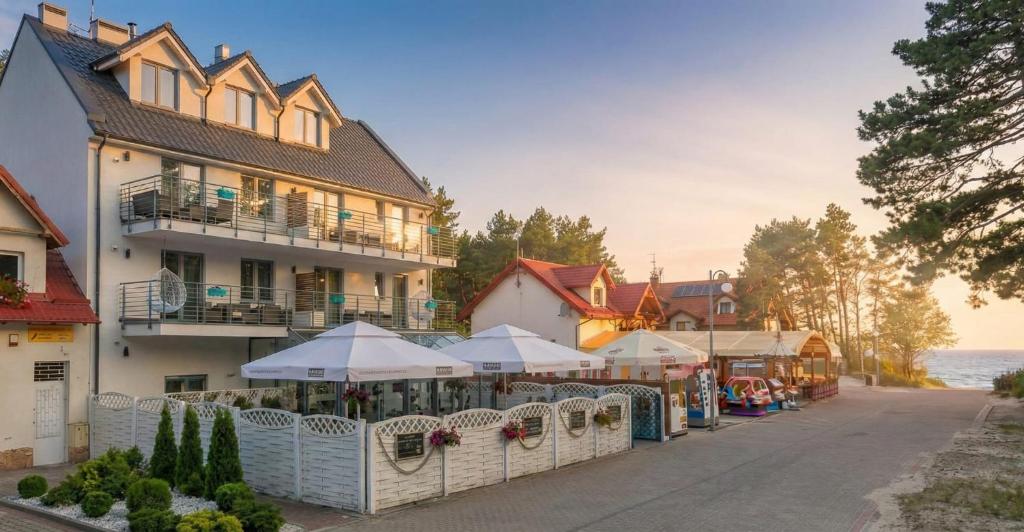 een gebouw met tafels en parasols op straat bij Rafa przy Plaży in Sztutowo