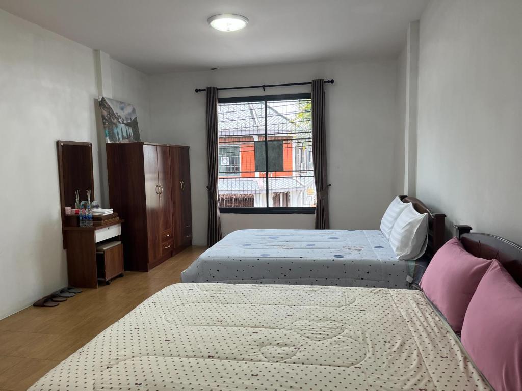 een slaapkamer met twee bedden en een raam bij Two Sisters Suratthani in Ban Don Rak