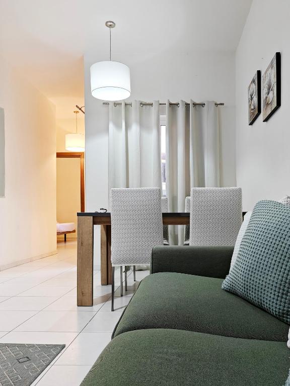 a dining room with a green couch and chairs at Speranza in Il-Gżira