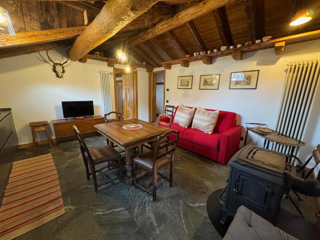 a living room with a table and a red couch at We Are 4810 LA CORDE D'ESCALADE in Courmayeur