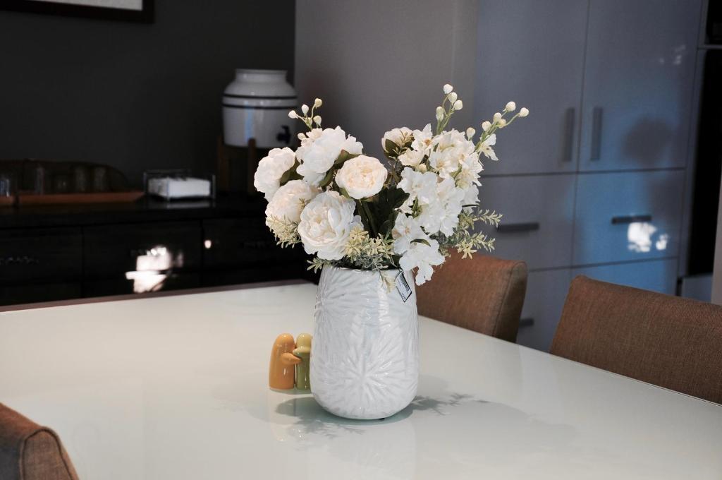 un jarrón blanco lleno de flores blancas en una mesa en TL Warmest Homestay en Gold Coast
