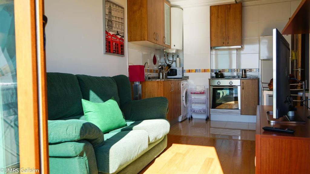 a living room with a green couch and a kitchen at Apartamentos Casangular in San Pedro