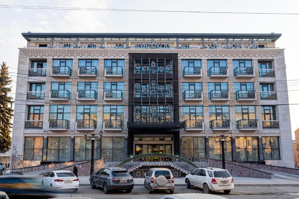 een gebouw met daarvoor geparkeerde auto's bij Hotel Aivazovsky in Gjoemri