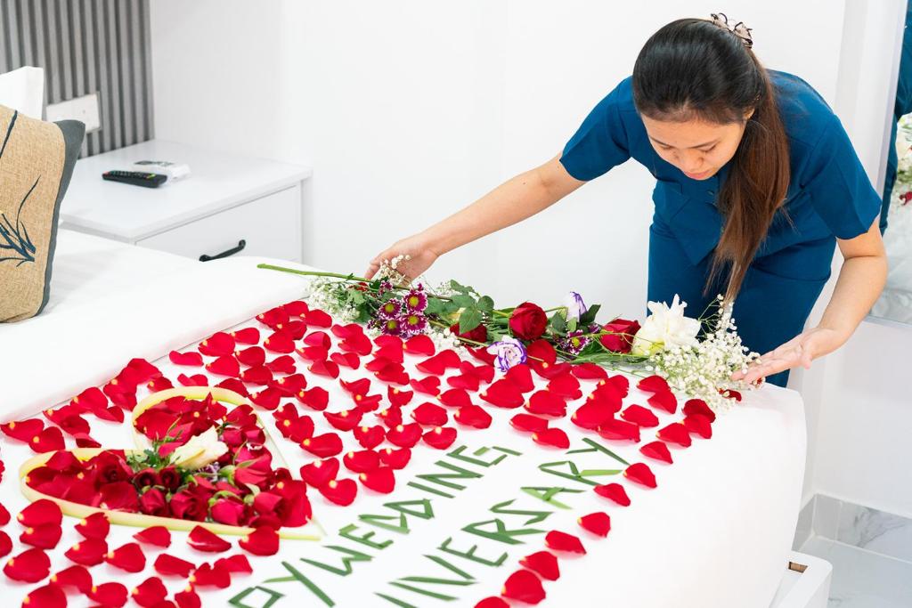 a woman cutting a birthday cake with roses on it at LemonRock Comfort in Male City
