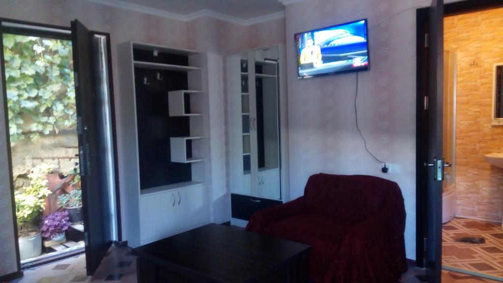 ein Wohnzimmer mit einem Stuhl und einem TV an der Wand in der Unterkunft Dadu's Apartment in Tbilisi City