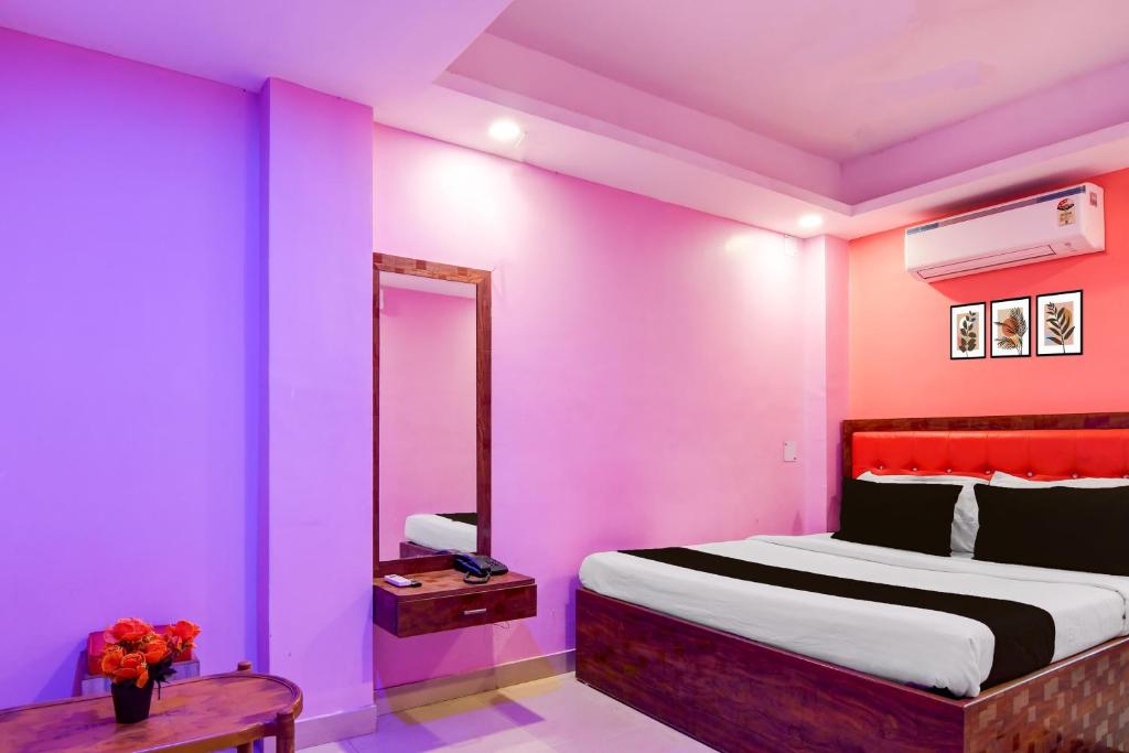 een slaapkamer met roze muren en een bed met een tafel bij Hotel O Golden Star in Ballygunge