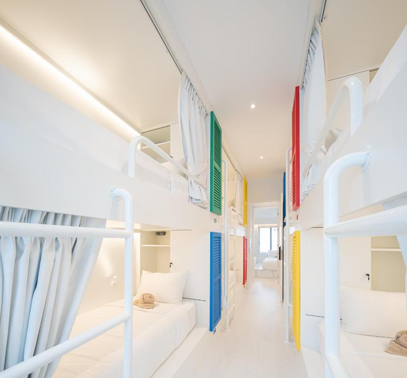 a room with white bunk beds and a corridor at Bedd Hostel in Bangkok