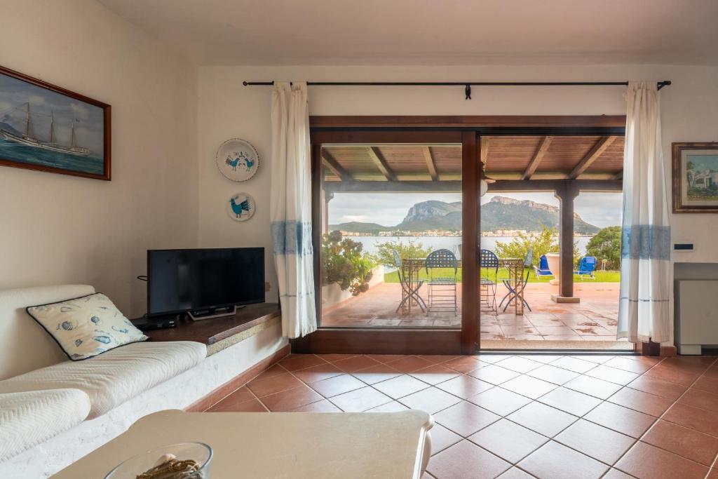 een woonkamer met een bank en een glazen schuifdeur bij Appartamento Baia Caddinas fronte mare in Golfo Aranci