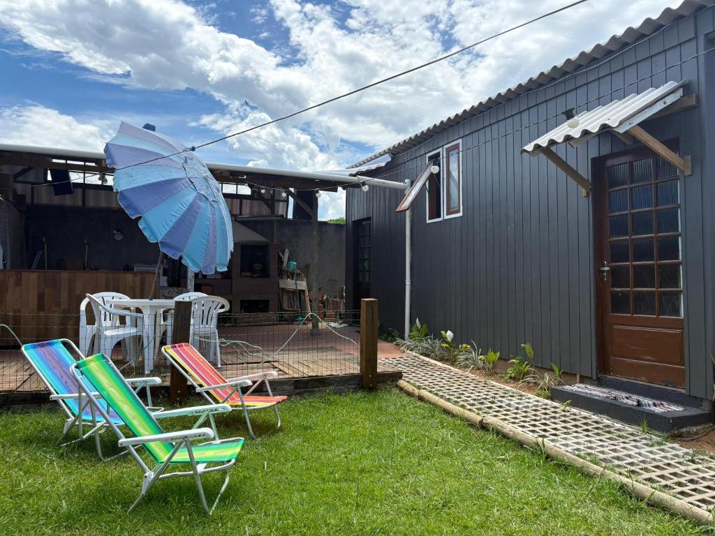 een groep stoelen en een paraplu in een tuin bij Chalé Amanhecer no Sul da Ilha in Florianópolis