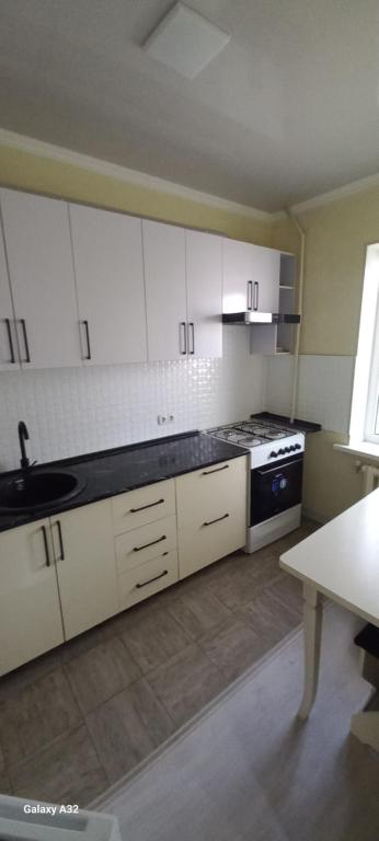 een keuken met witte kasten, een wastafel en een fornuis bij Апартаменты in Tasjkent