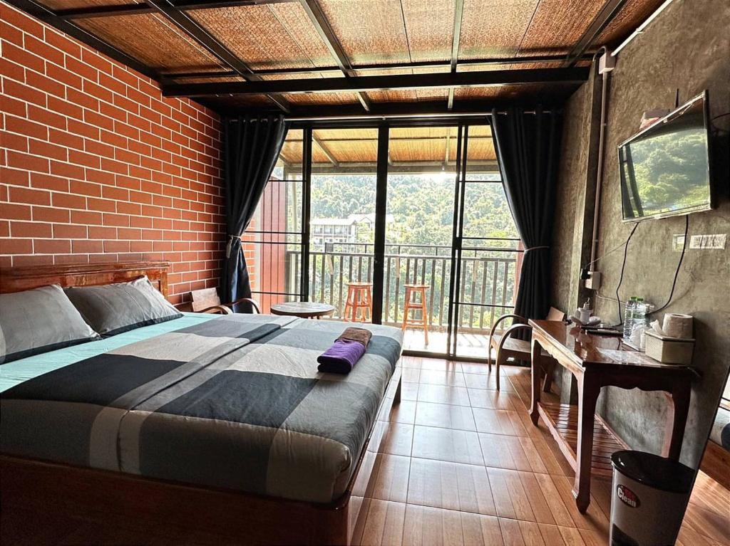 een slaapkamer met een bed en een groot raam bij pilokhillhouse บ้านอีต่องเหมืองปิล็อก in Ban Pilok Khi