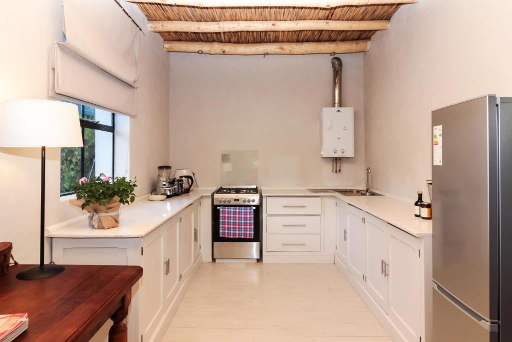 a kitchen with white cabinets and a wooden table at The Whyte House in Graaff-Reinet