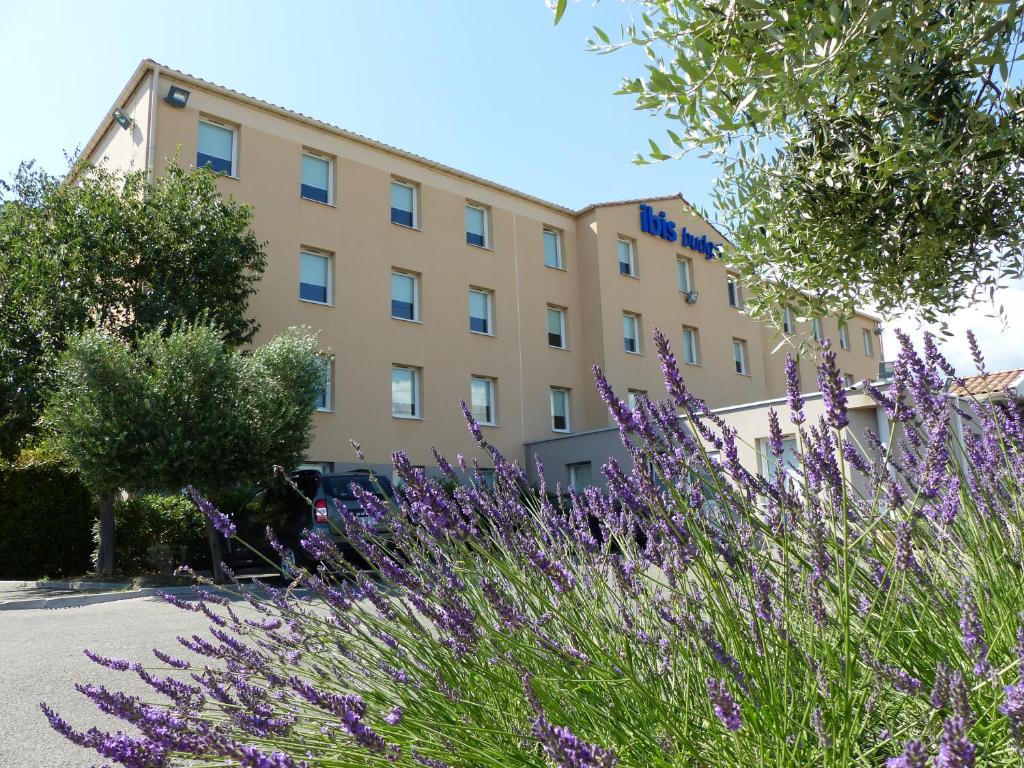 un edificio con flores púrpuras delante de él en Ibis Budget Marseille Valentine en Marsella