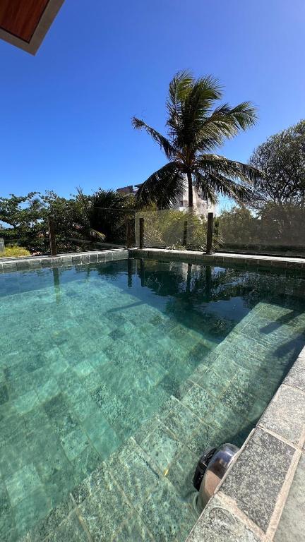 a swimming pool with a palm tree in the background at High Standard Two Bedroom Apartment Private Pool Frances Beach Garden 209 in Marechal Deodoro