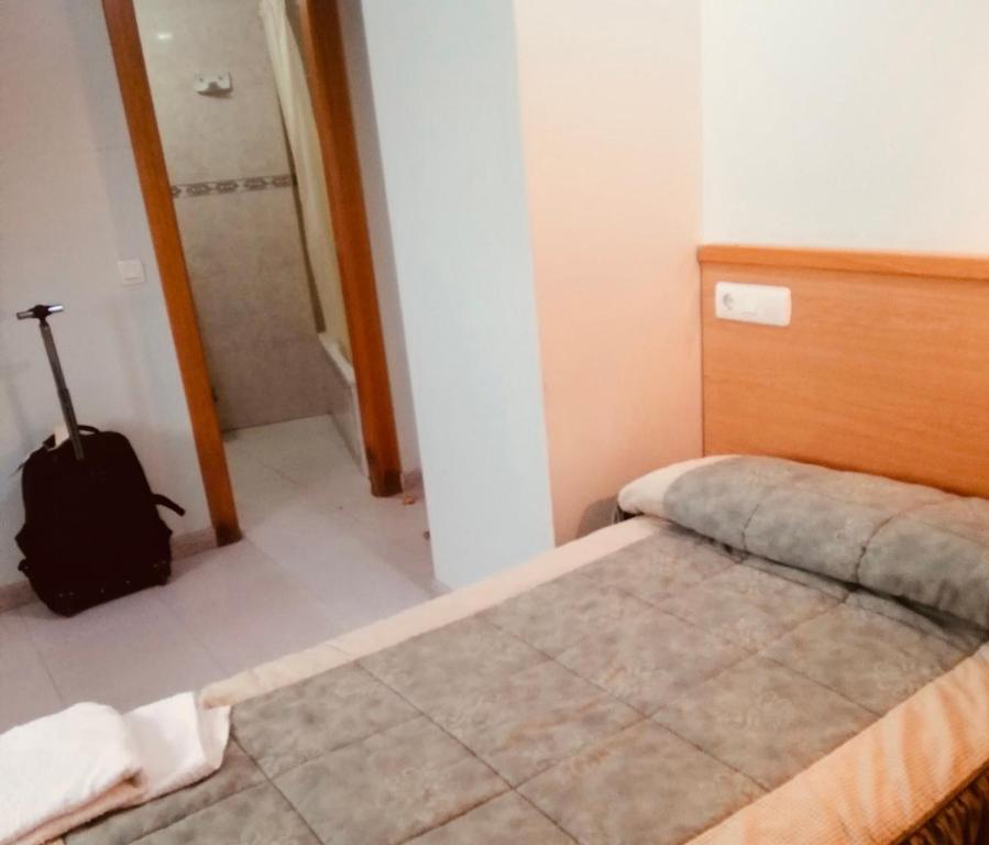 une chambre avec un lit et une valise dedans dans l'établissement Hostal Libertad, à Villadangos del Páramo