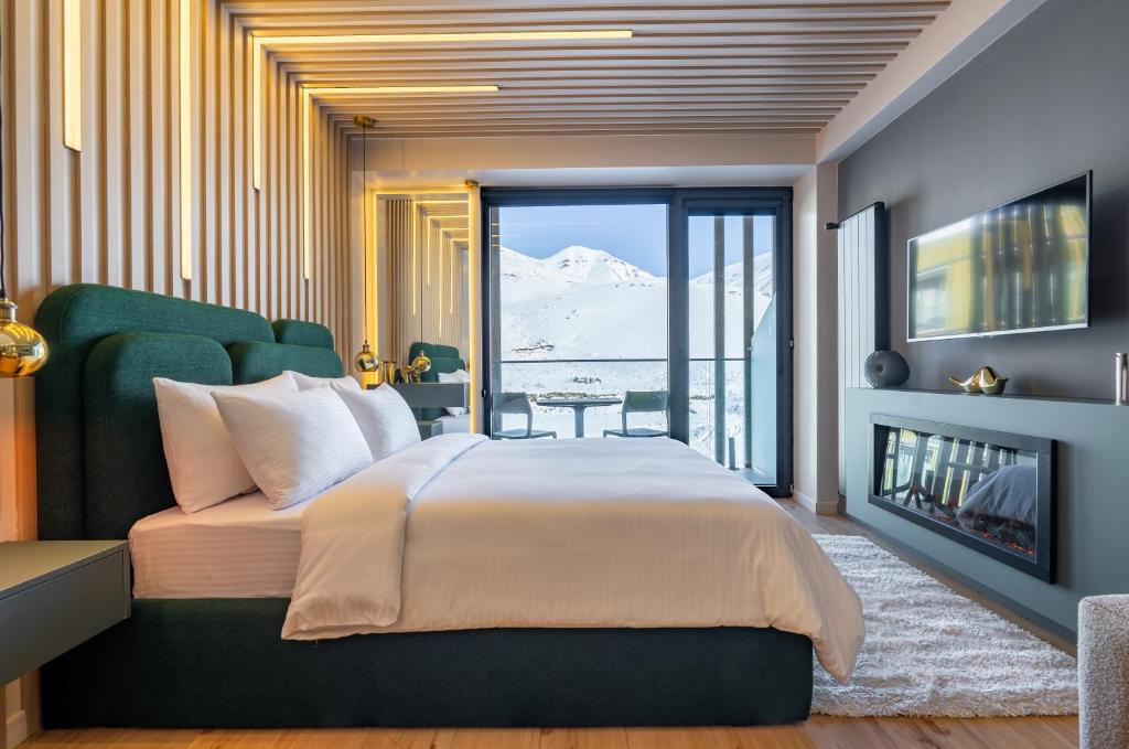 een slaapkamer met een groot bed en een open haard bij New Gudauri Atrium Apartments in Goedaoeri