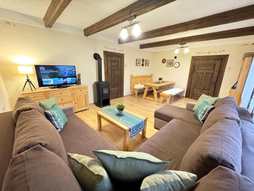 een woonkamer met een bank en een tv bij Przystanek Rabka - Domek całoroczny in Rabka