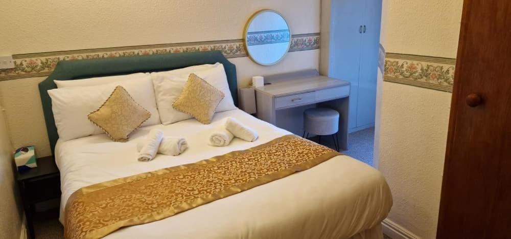 een slaapkamer met een groot wit bed met een spiegel bij Lily Hotel Blackpool in Blackpool