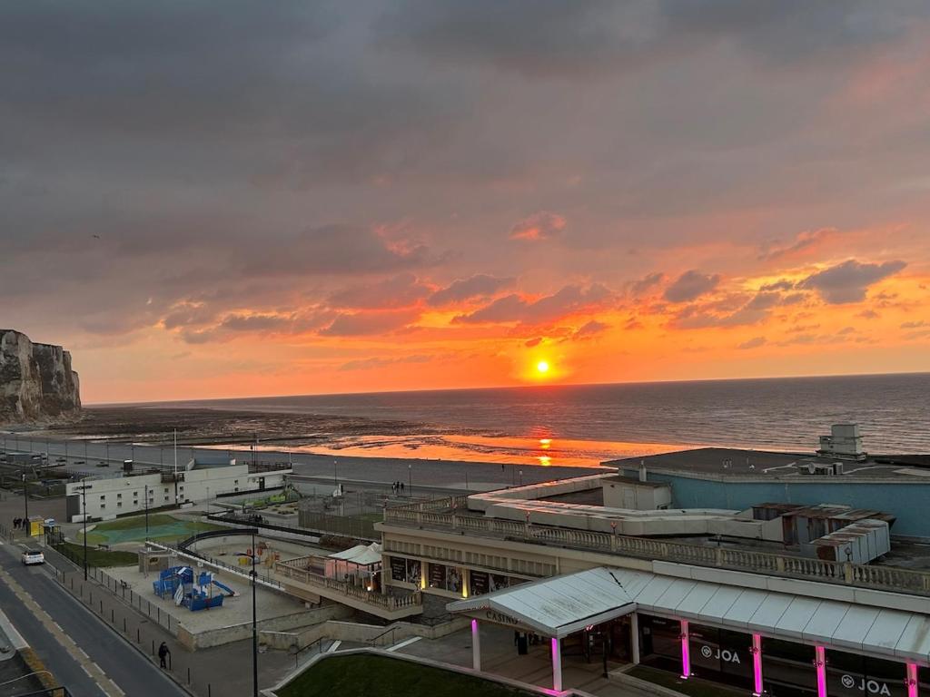 a sunset over a city with the ocean in the background at Le Gouvernail in Le Tréport