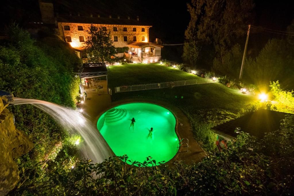 una piscina verde en medio de un patio por la noche en Font del Pas en Beceite