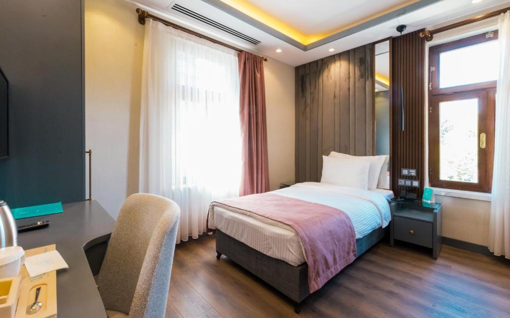 een slaapkamer met een bed, een bureau en een raam bij VE Hotels Adakale in Yenişehir