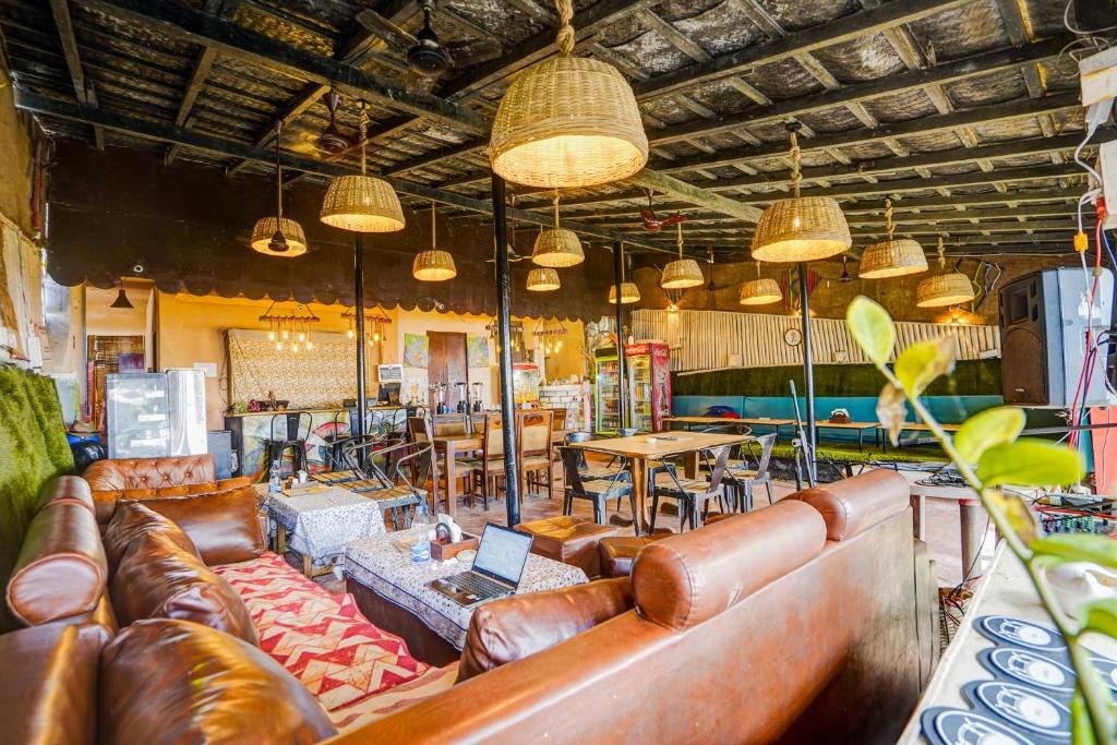 ein Wohnzimmer mit Ledersofas, Tischen und Lampen in der Unterkunft Hotel O Arambol Beach Formerly Hakuna Matata in Arambol