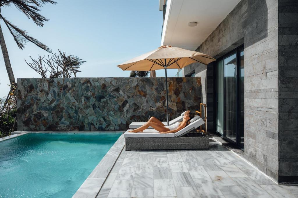 a woman laying on a chair next to a swimming pool at Radisson Resort Mui Ne in Mui Ne