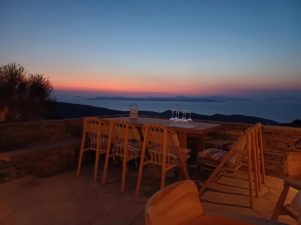 a wooden table with chairs and wine glasses on it at ARIA Kea Sunset Homes in Ioulis