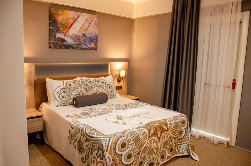 una camera d'albergo con un letto grande con un copriletto bianco di ida efes a Selçuk