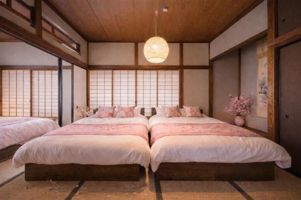 twee bedden in een kamer met ramen bij Winter Retreat in a Renovated Traditional House - Family-Friendly Play Area - Sunrise by the Sea - Easy Access to Kamakura and Hakone - Macchiato SHONAN Vacation Stay in Hiratsuka