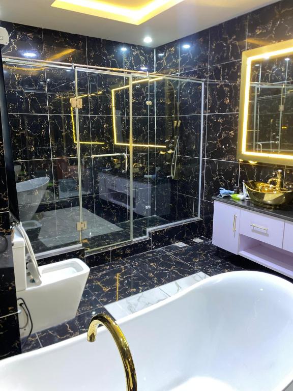a bathroom with a tub and a shower with black tiles at Boho apartment and spa in Lekki