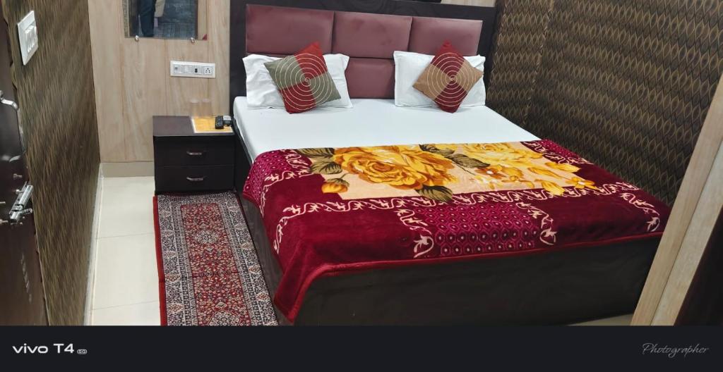 een slaapkamer met een bed met een rode sprei bij Shree Radha Raman Palace in Ayodhya