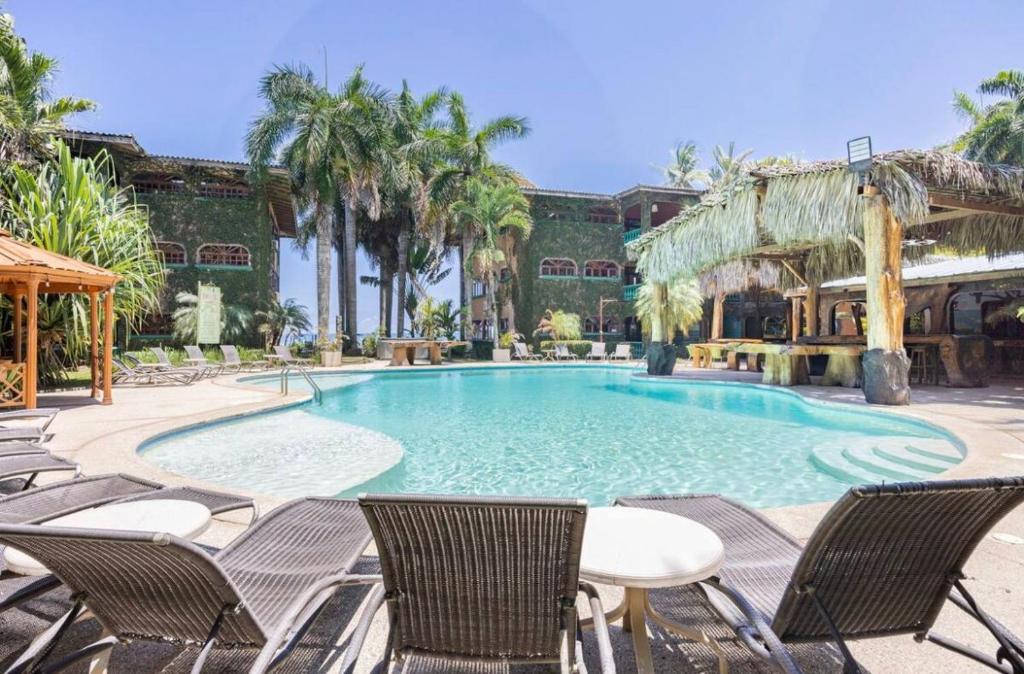 une grande piscine avec des chaises et une table dans l'établissement Host Company Jaco Luxury, à Jacó